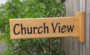 Solid oak wooden sign extruding from a solid oak backplate which is attached to the surface with four simple screw fixings, providing a 180 view, with engraved lettering painted with black paint finished with 3 coats of osmo oil.